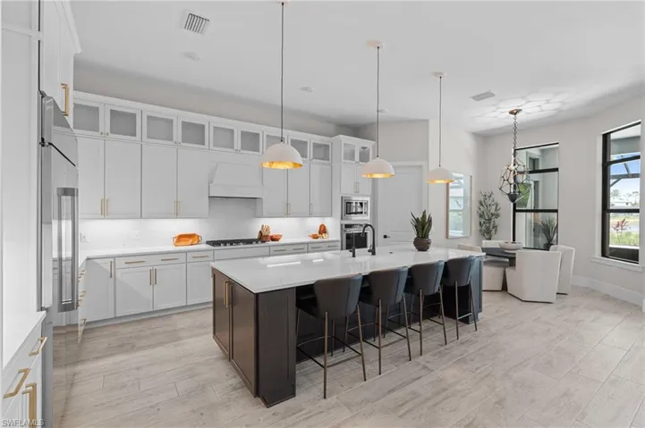 Kitchen featuring stainless steel appliances, light countertops, white cabinets, a kitchen bar, and light wood-type flooring