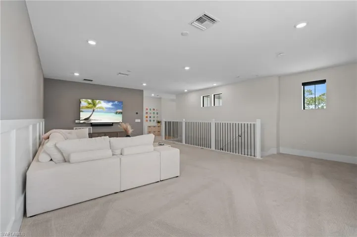 Carpeted living room with baseboards, visible vents, and recessed lighting