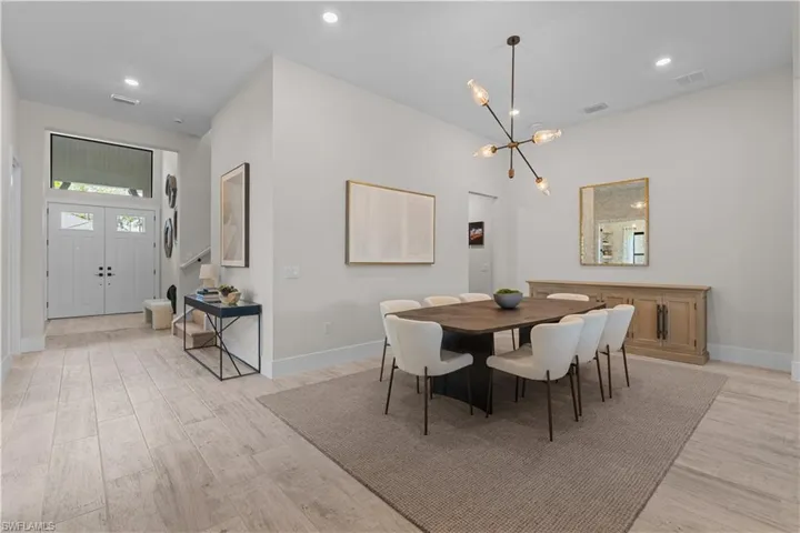 Dining room featuring light wood-style floors, a chandelier, baseboards, and recessed lighting