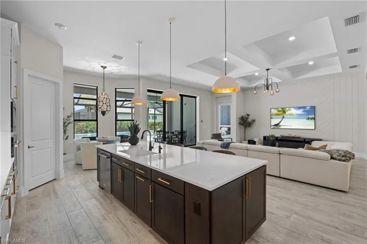 Kitchen with a sink, coffered ceiling, an inviting chandelier, open floor plan, and light wood finished floors