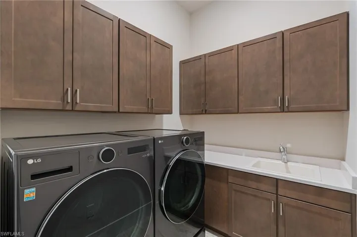 Laundry area featuring a sink, cabinet space, and washing machine and clothes dryer