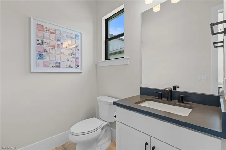 Bathroom featuring baseboards, toilet, and vanity