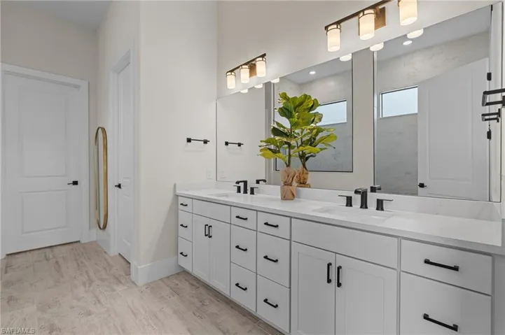 Bathroom with baseboards, wood finished floors, double vanity, and a sink