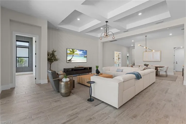 Living area featuring an inviting chandelier, coffered ceiling, light wood finished floors, baseboards, and visible vents