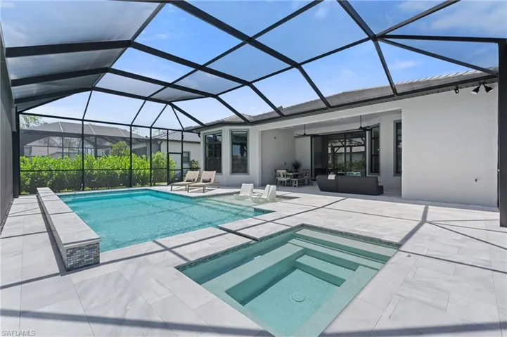 Outdoor pool with a patio, glass enclosure, a ceiling fan, and an in ground hot tub