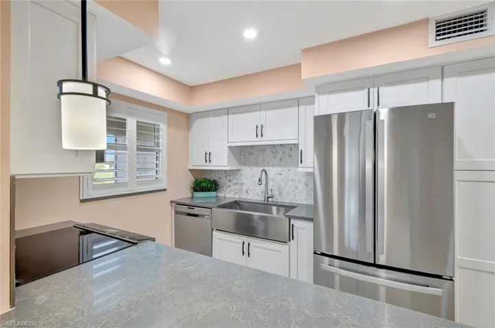 Kitchen featuring stainless steel appliances, white cabinets, decorative backsplash, dark stone counters, and recessed lighting