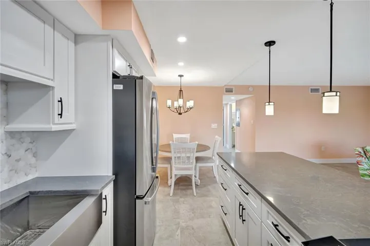 Kitchen with white cabinetry, freestanding refrigerator, and dark stone countertops