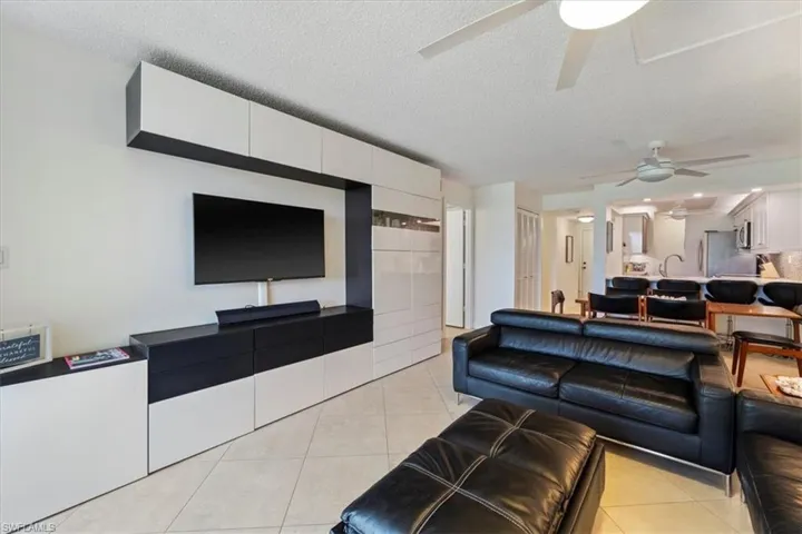 Living area with a textured ceiling, light tile patterned floors, and a ceiling fan