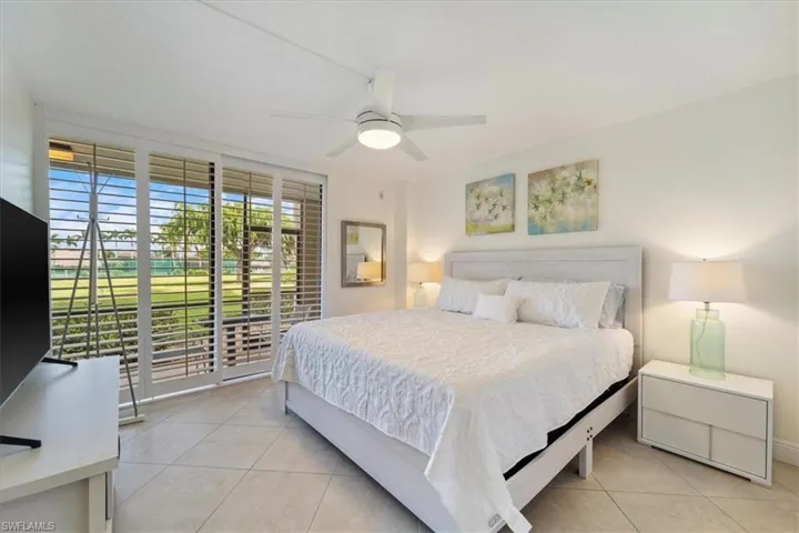 Bedroom featuring access to outside, light tile patterned flooring, ceiling fan, and floor to ceiling windows