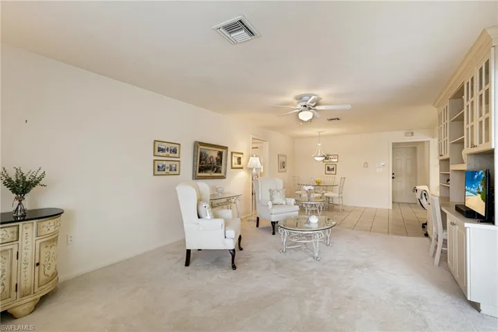 Living area featuring ceiling fan, light colored carpet, and baseboards