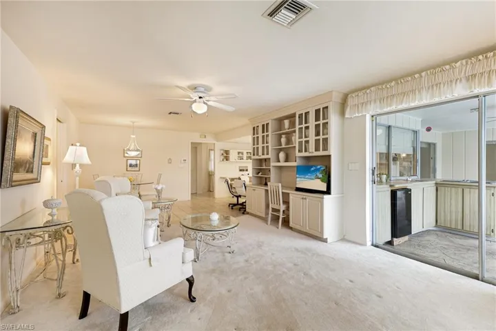 Living area featuring light colored carpet and ceiling fan