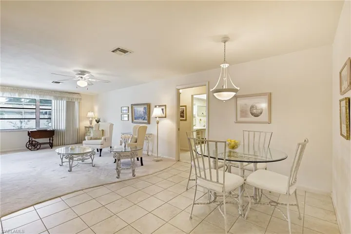 Dining space featuring light tile patterned flooring, light colored carpet, a ceiling fan, and baseboards