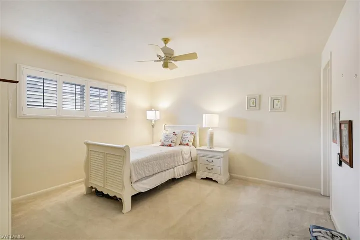 Bedroom featuring light colored carpet, baseboards, and a ceiling fan
