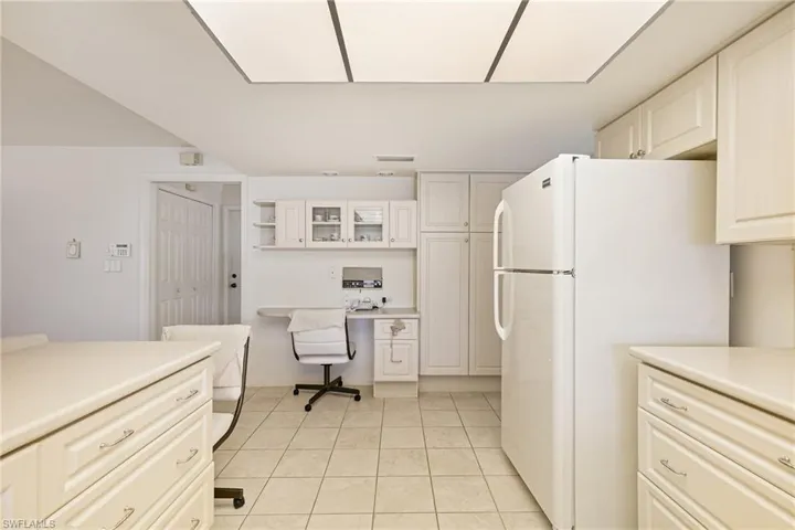 Kitchen with freestanding refrigerator, light countertops, light tile patterned floors, and white cabinets