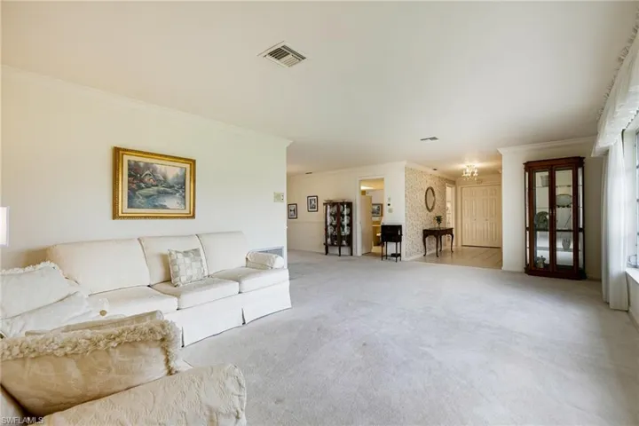 Living room with crown molding and light colored carpet