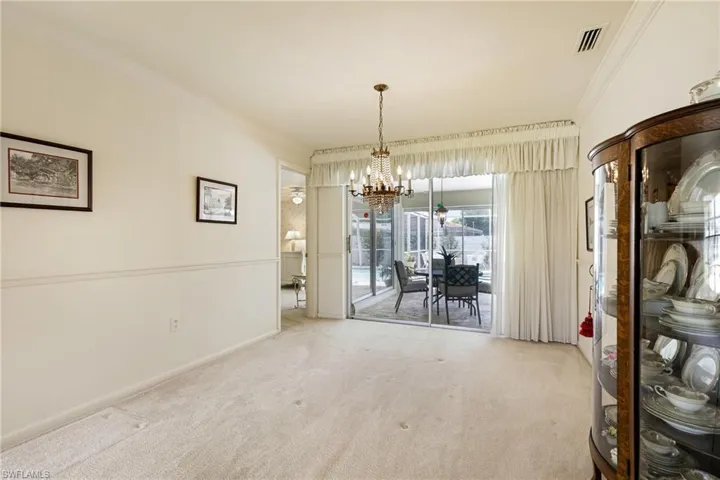 Carpeted dining area with a chandelier, crown molding, and baseboards