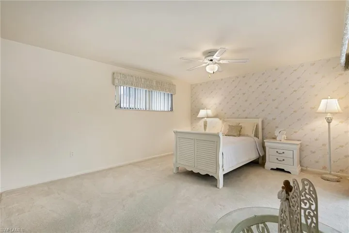 Carpeted bedroom featuring baseboards, wallpapered walls, and a ceiling fan
