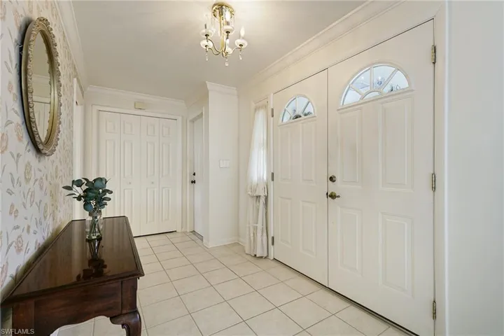 Entrance foyer featuring a chandelier, light tile patterned flooring, and ornamental molding