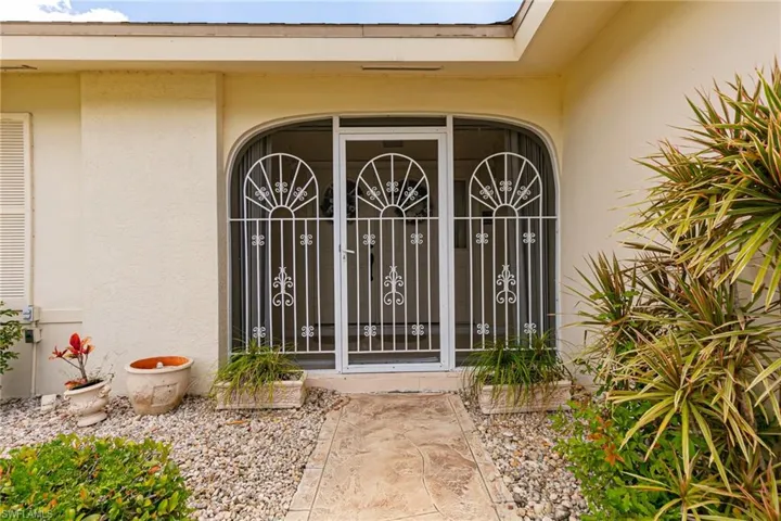 Doorway to property with stucco siding and a gate