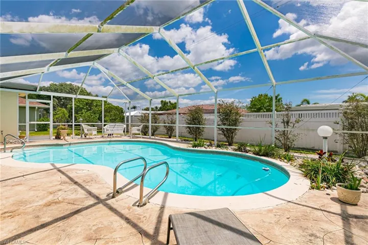 View of pool with fence, a patio area, and glass enclosure