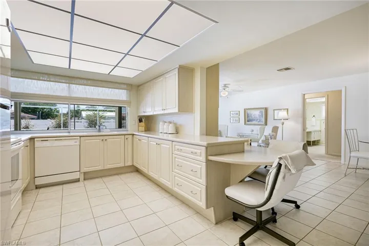 Kitchen featuring white dishwasher, light tile patterned flooring, a sink, and a peninsula