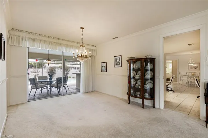 Dining space with carpet floors, a chandelier, tile patterned flooring, and crown molding