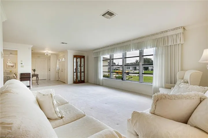 Living room with light carpet, a chandelier, and ornamental molding