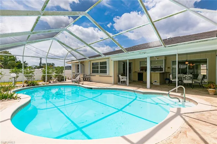 View of swimming pool featuring a patio, fence, and a lanai