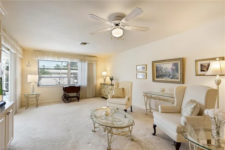 Living area featuring light colored carpet, ceiling fan, and baseboards