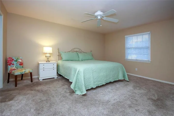 Carpeted bedroom with ceiling fan and baseboards