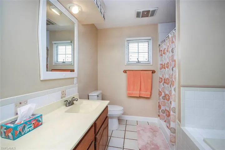Full bathroom with light tile patterned floors, vanity, a shower with curtain, and a bath