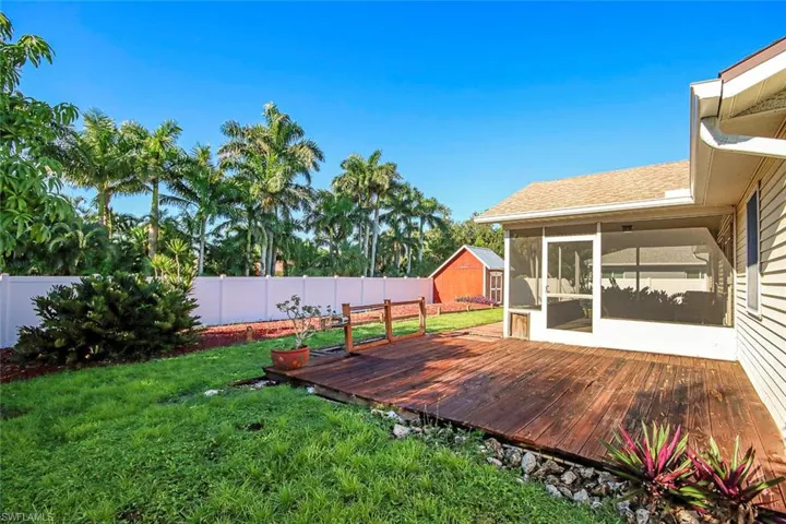 Fenced backyard with a deck, a sunroom, and a storage unit