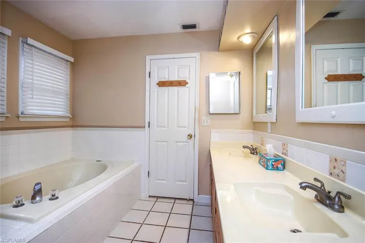 Bathroom with light tile patterned flooring, a garden tub, and double vanity