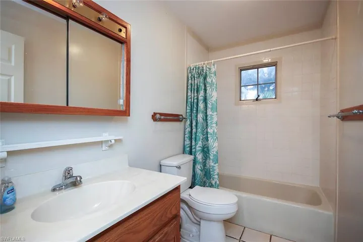 Full bath with shower / tub combo with curtain, vanity, and tile patterned flooring