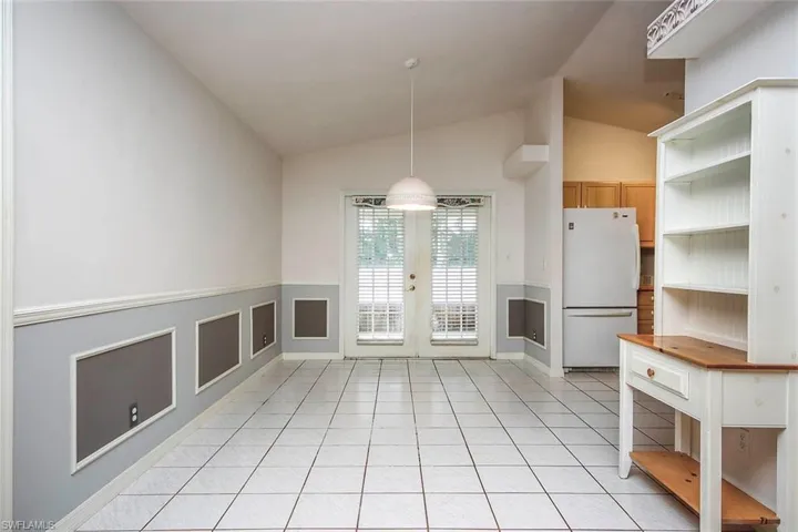 Unfurnished dining area featuring lofted ceiling, light tile patterned flooring, and french doors