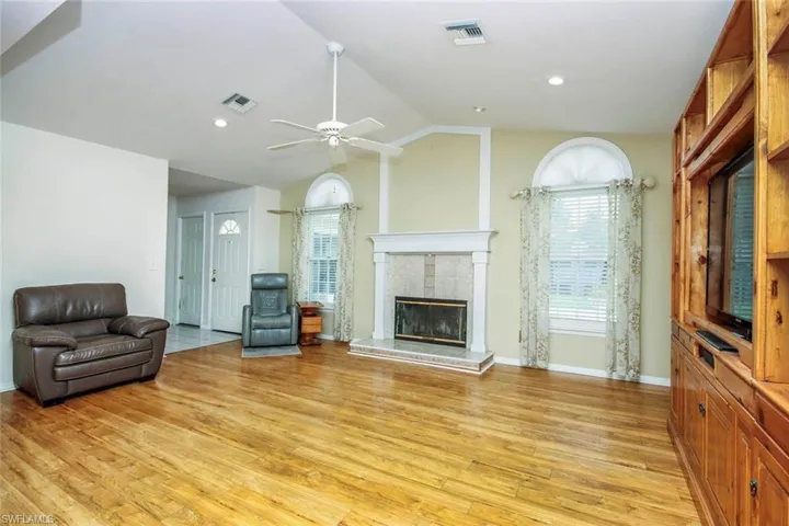 Living area featuring a fireplace, lofted ceiling, ceiling fan, light wood-type flooring, and recessed lighting