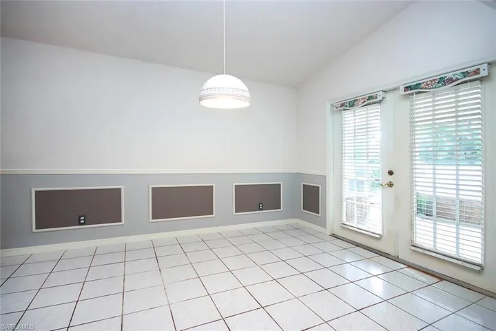 Spare room with light tile patterned floors, lofted ceiling, and french doors