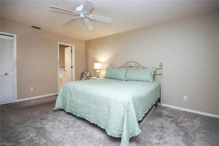 Carpeted bedroom featuring ceiling fan, connected bathroom, and a closet