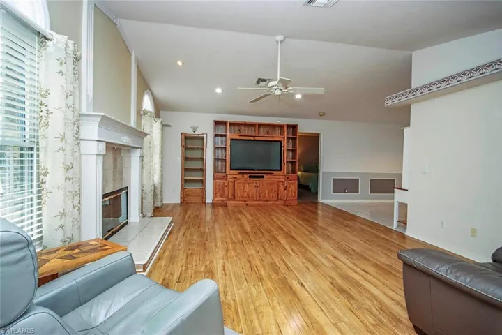 Living room featuring vaulted ceiling, a tile fireplace, ceiling fan, light wood-style flooring, and recessed lighting