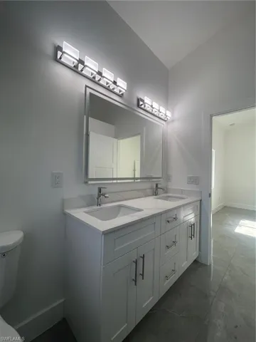 Bathroom with dual bowl vanity, tile patterned floors, and toilet