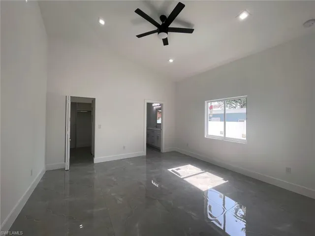 Tiled empty room with ceiling fan and high vaulted ceiling
