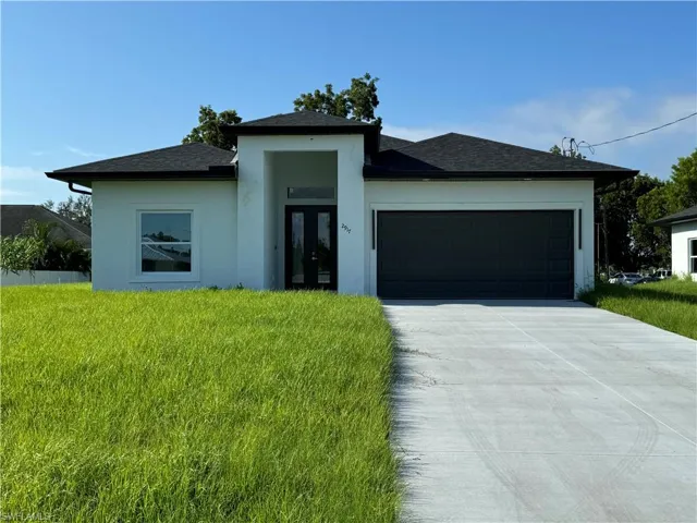 Prairie-style home featuring a shingled roof, stucco siding, an attached garage, and concrete driveway