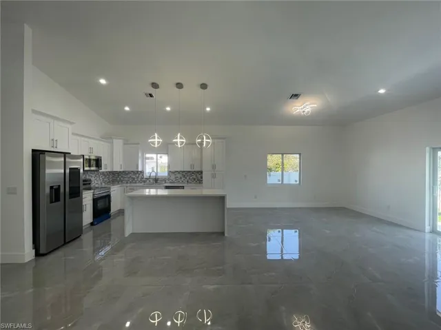 Kitchen featuring appliances with stainless steel finishes, tile patterned floors, a kitchen island, and white cabinetry