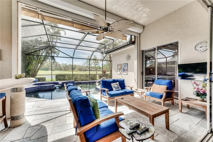 View of patio with glass enclosure, ceiling fan, a pool with connected hot tub, and outdoor lounge area