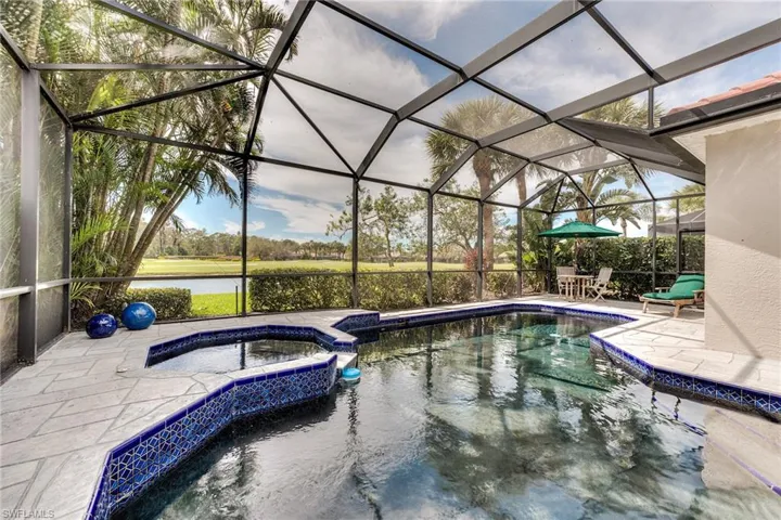 View of swimming pool with glass enclosure, a pool with connected hot tub, a water view, and a patio