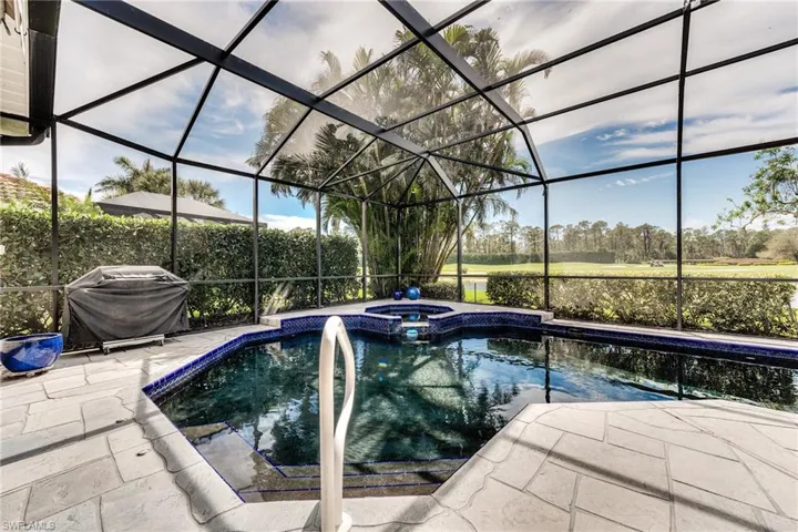 View of swimming pool with a grill, a pool with connected hot tub, glass enclosure, and a patio