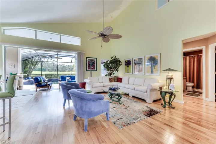 Living area with hardwood / wood-style flooring, ceiling fan, high vaulted ceiling, and a sunroom