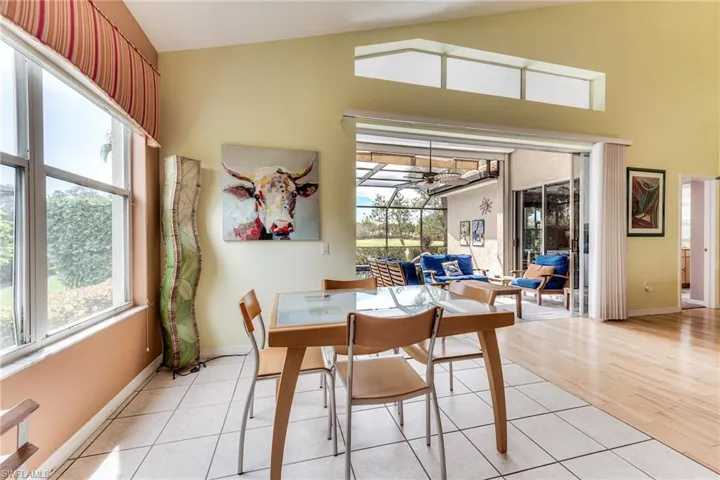 Dining space featuring high vaulted ceiling, ceiling fan, light wood-style flooring, and baseboards