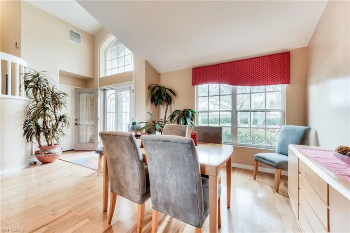 Dining room with high vaulted ceiling, visible vents, light wood-style flooring, and baseboards