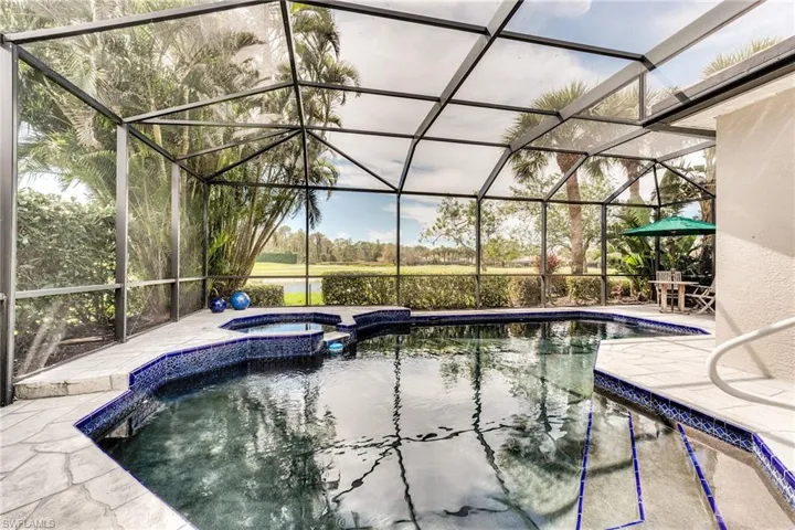 View of swimming pool with a patio, glass enclosure, and a pool with connected hot tub